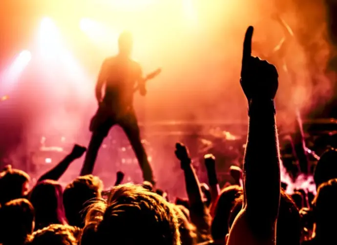 view from crowd cheering rock band performing on stage^ guitarist in silhouette