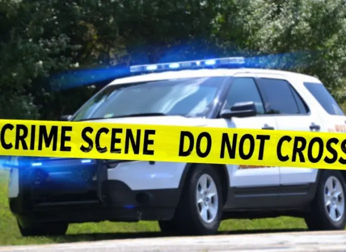 Sheriff Department vehicle with emergency lights on behind Crime Scene tape