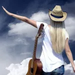 Young woman with guitar on the road and her vintage baggage