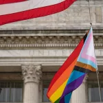 Waving Pride LGBT flag next to the flag of USA