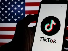 Photo illustration of TikTok logo displayed on a smartphone with American Flag in the background.