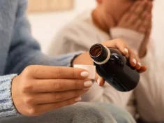 Mother giving cough syrup to her sick son in bed