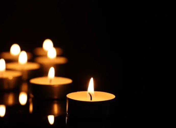 Burning candles on mirror surface in darkness^ closeup