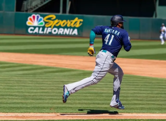Seattle Mariners infielder Carlos Santana runs to first base against the Oakland Athletics at the Oakland Coliseum. Oakland^ California - August 21^ 2022