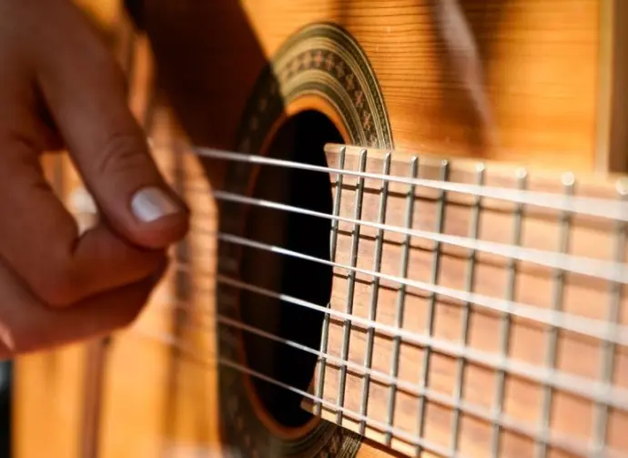 A woman plays an acoustic guitar.