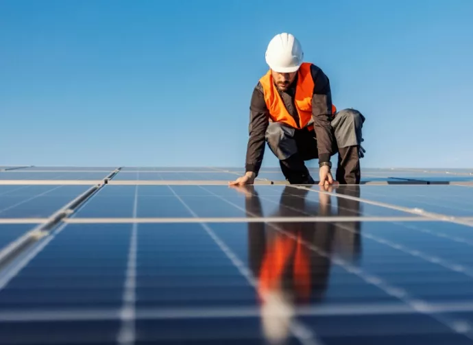 A worker installing solar panels on the roof