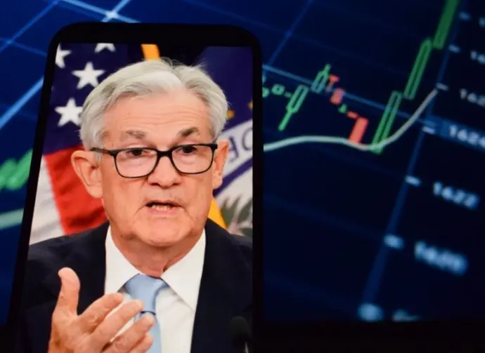 On the smartphone screen^ Federal Reserve (Fed) Chair Jerome Powell is visible. In the background^ an inflation rate chart is displayed. 19.04.2025. New York^ U.S