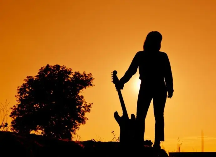 Silhouette Hipster woman with guitars in the meadow.