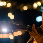 Man play acoustic guitar at outdoor concert with a microphone stand in the front^ musical concept.