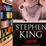 Paperback cover of Carrie by Stephen King shown on a bookshop shelf background