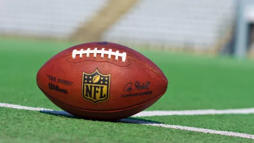 Official ball of the NFL football league on grass turf background.
