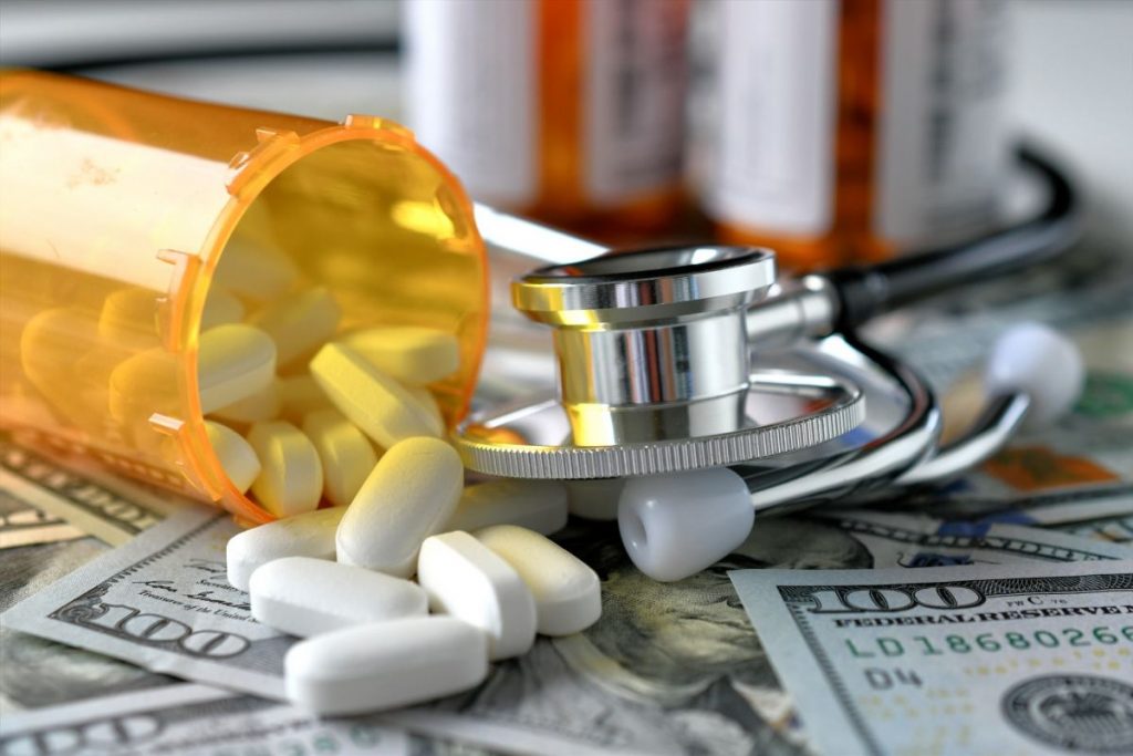 a-stethoscope-laying-on-medicine-white-pills-and-money-with-an-rx-prescription-drug-bottles-1024x683-1