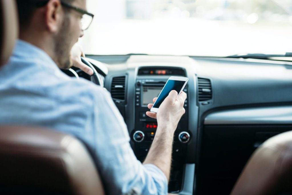 businessman-ignoring-safety-and-texting-on-mobile-phone-while-driving-1024x683-1