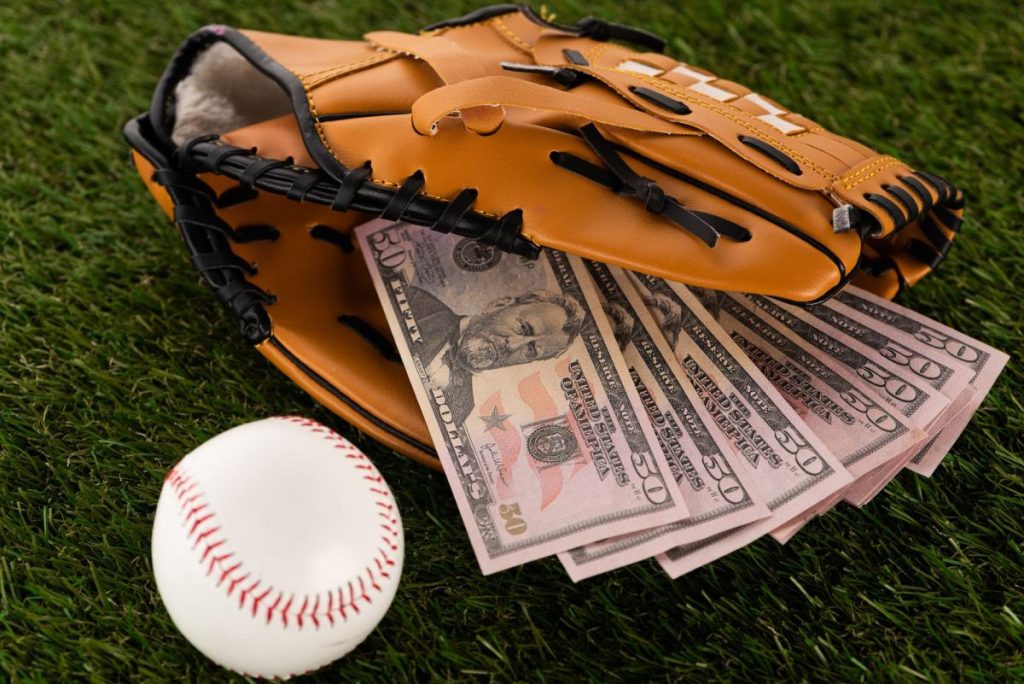 dollar-banknotes-in-baseball-glove-near-ball-on-green-grass-sports-betting-concept-1024x684127129-1