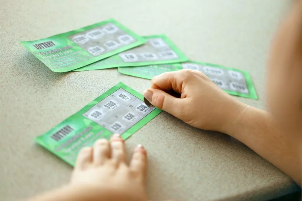 close-up-view-of-silver-coin-in-hand-of-gambler-scratching-fake-lottery-card-1024x683237614-1