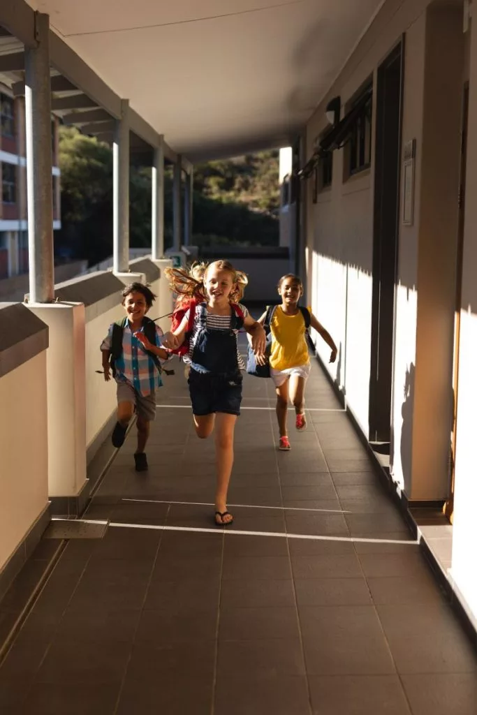 front-view-of-schoolkids-with-schoolbags-running-in-hallway-of-elementary-school-683x1024489097-1