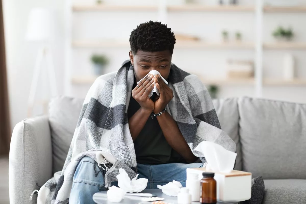 sick-black-guy-sitting-at-couch-sneezing408106