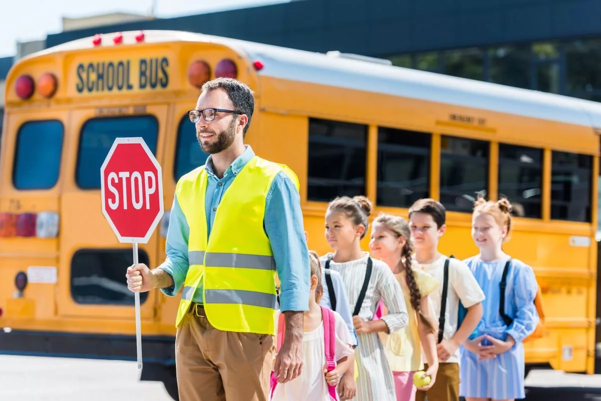 traffic-guard-crossing-road-with-schoolchildren-in-front-of-school-bus644192
