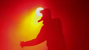 Silhouette of rap singer with microphone in hand. Rapper performing on concert.