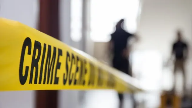 crime scene tape in building with blurred forensic team background