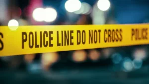 Yellow Tape Showing Text "Police Line Do Not Cross" Restricting a Crime Scene Area At Night. Close Up Aesthetic Shot with Bokeh Effect and Flickering Lights.