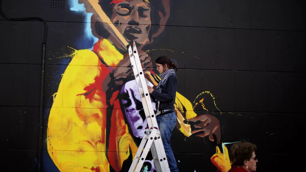 a-woman-paints-graffiti-of-the-rock-star-jimi-hendrix-on-the-wall-of-a-music-shop-in-malaga-2