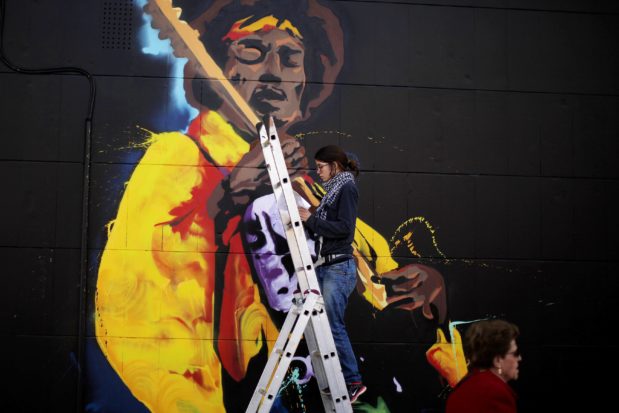 a-woman-paints-graffiti-of-the-rock-star-jimi-hendrix-on-the-wall-of-a-music-shop-in-malaga-2