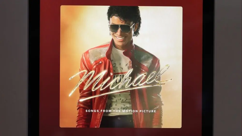 An Apple iPad displays the Spotify music player featuring the artist Michael Jackson's album "Michael: Songs from the Motion Picture"