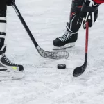 close-up of hockey puck^ sticks^ two players on ice during the game