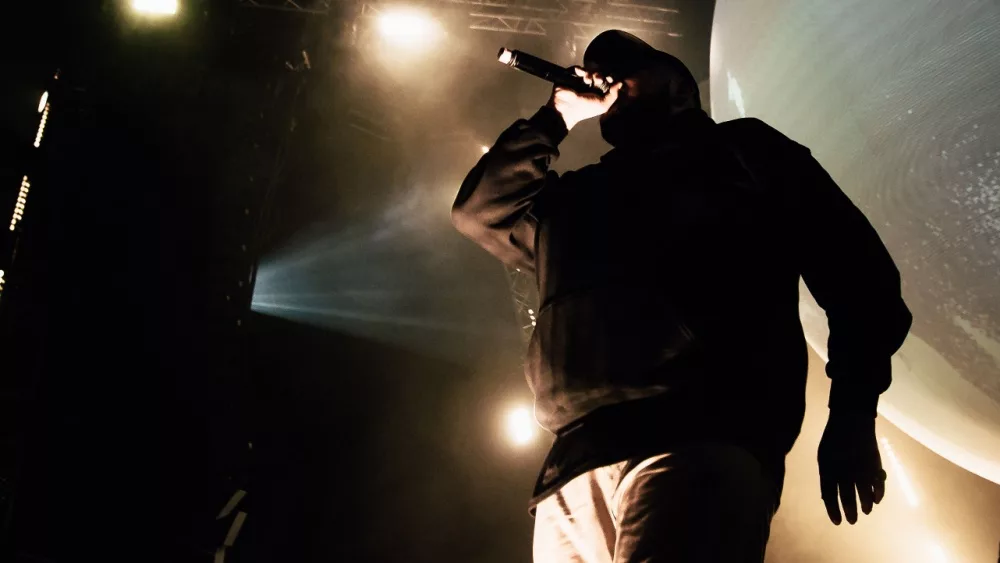 Rapper in hoody with microphone on the stage.