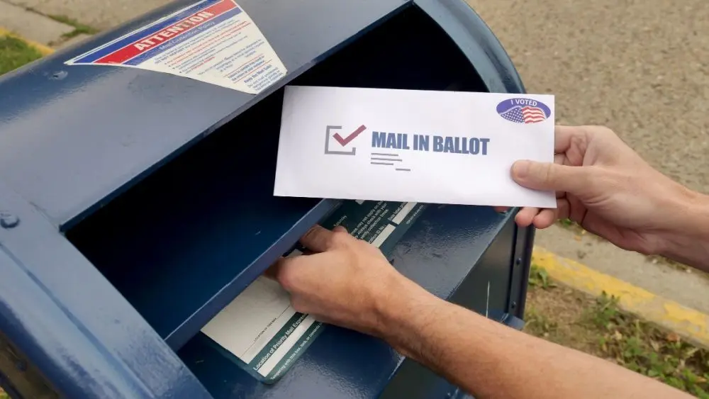 A man puts an absentee mail-in ballot in the mailbox. Circa August^ 2020