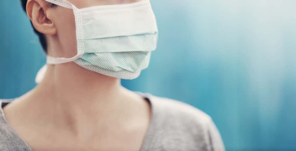woman with paper surgical mask on only top of nose to shoulders visible