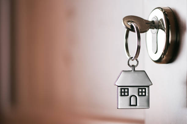 house-key-on-a-house-shaped-silver-keyring-in-the-lock-of-a-door