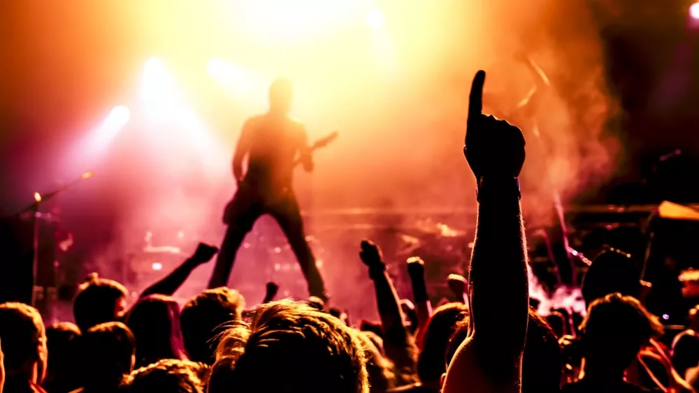 silhouette of guitar player in action on stage in front of concert crowd