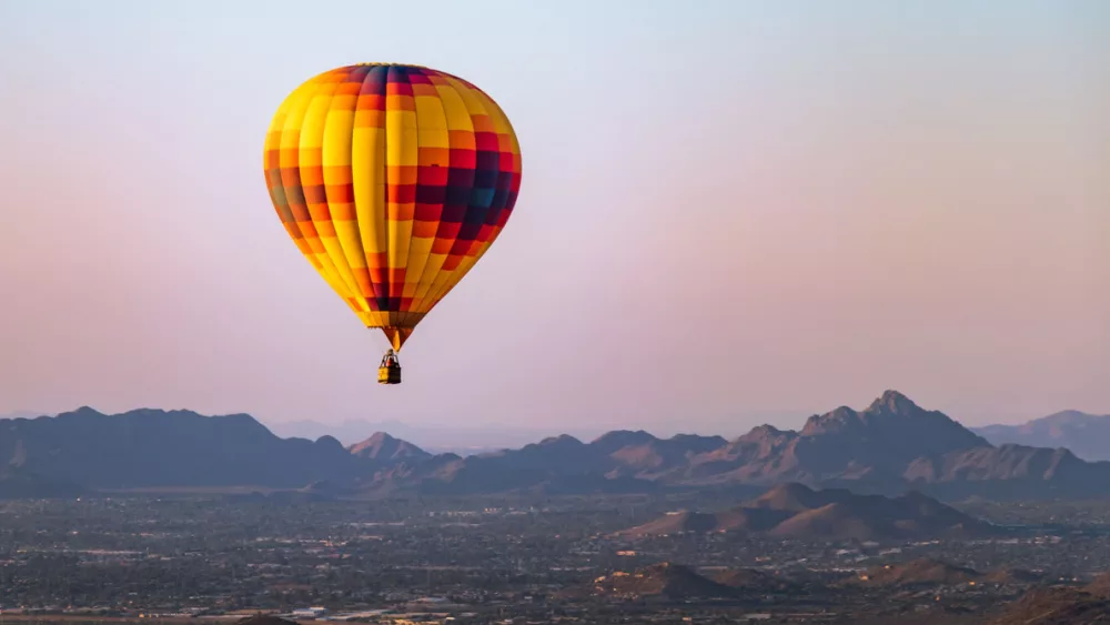 Hot air balloon flies over phoenix^ Arizona with Sonoran Desert in background