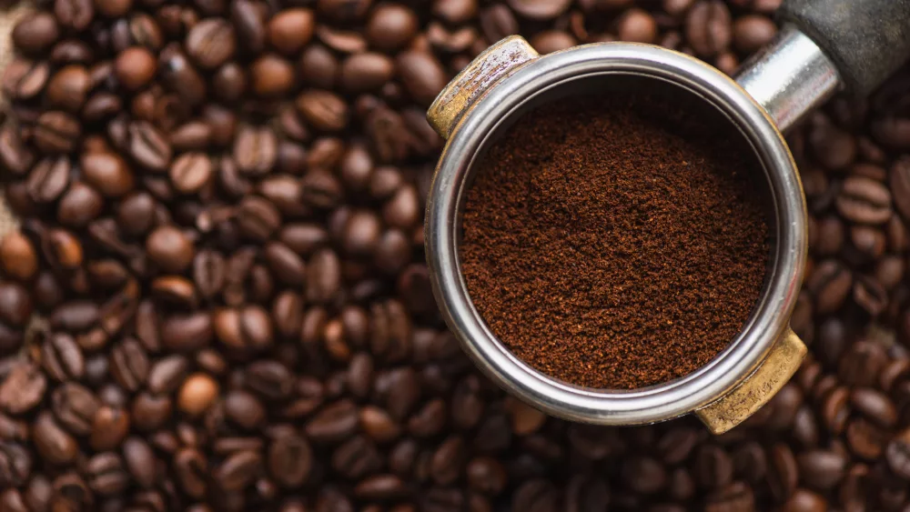 top-view-of-ground-coffee-in-portafilter-on-coffee-beans-background