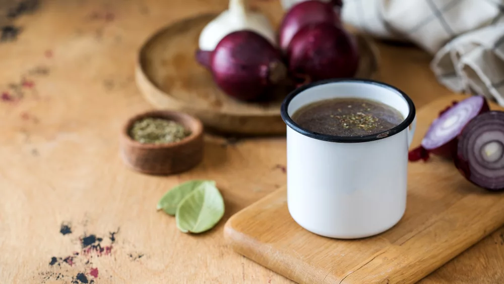 homemade-healthy-bone-broth-with-spices-in-a-white-mug-on-a-wooden-board