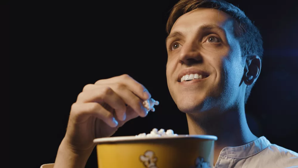 smiling-man-watching-a-movie-and-eating-popcorn-2