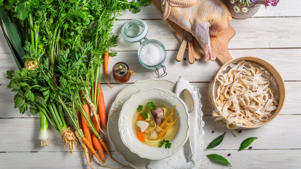 homemade-chicken-noodle-soup-with-ingredients-on-wooden-table