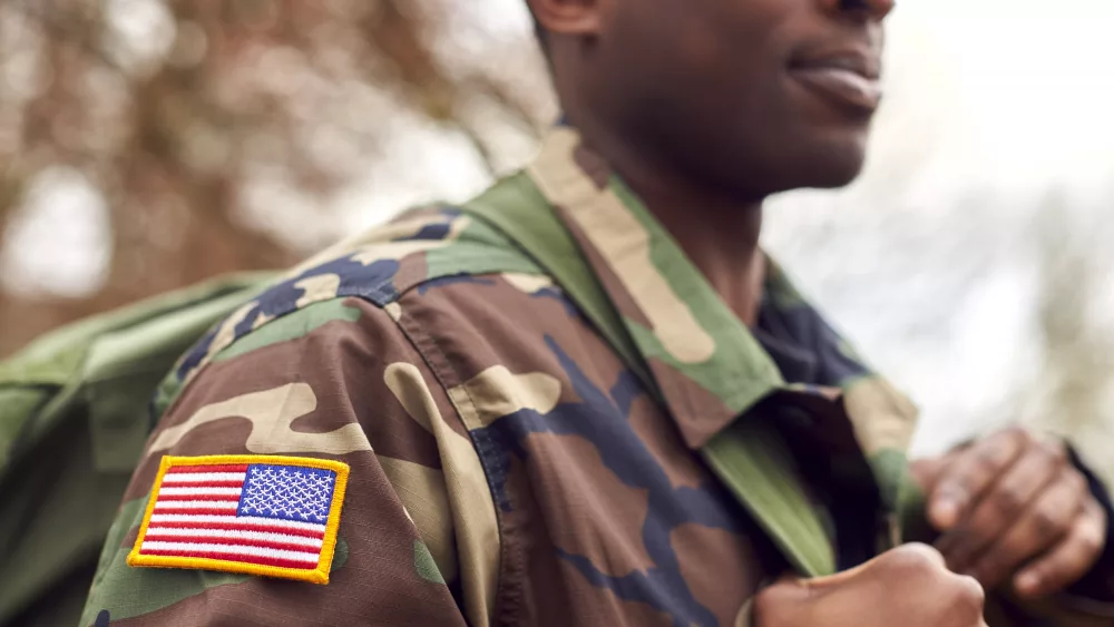 close-up-of-american-flag-on-uniform-of-soldier-carrying-kitbag-returning-home-on-leave