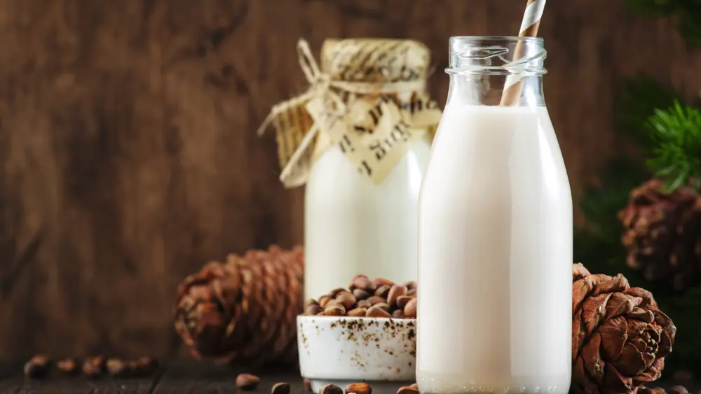 vegan-cedar-nut-milk-in-bottles-closeup-wooden-table-backgroun