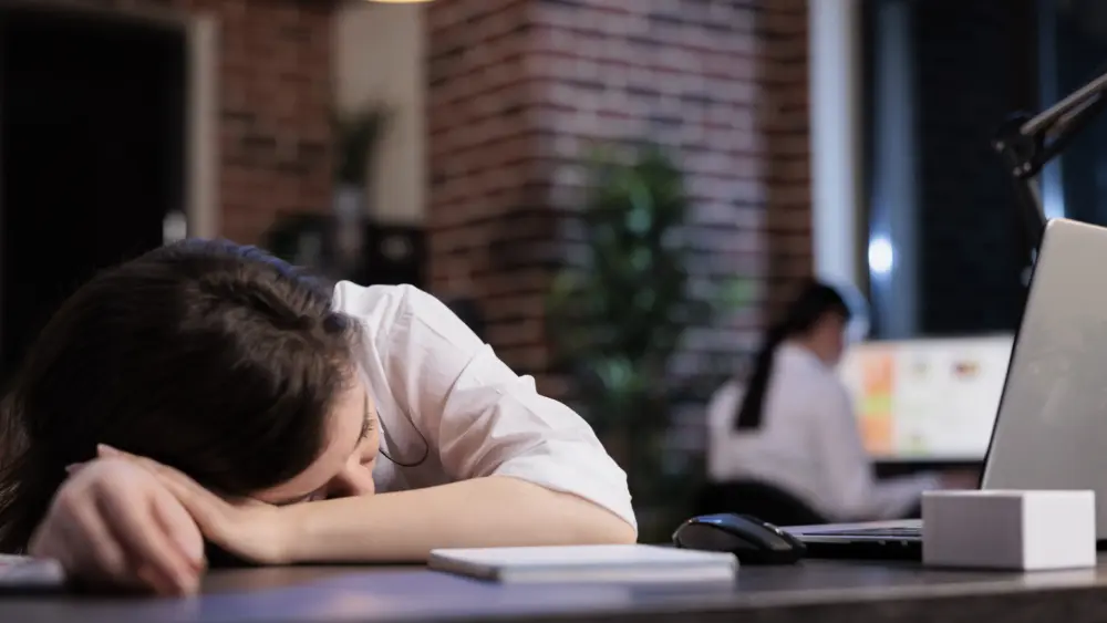 fatigued-marketing-agency-employee-sleeping-on-desk-because-of-overtime-working-hours-at-night