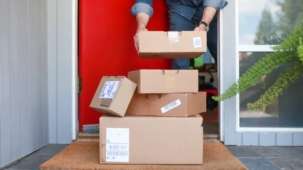 man-picking-up-delivered-packages-from-the-porch-2024-11-26-10-46-08-utc