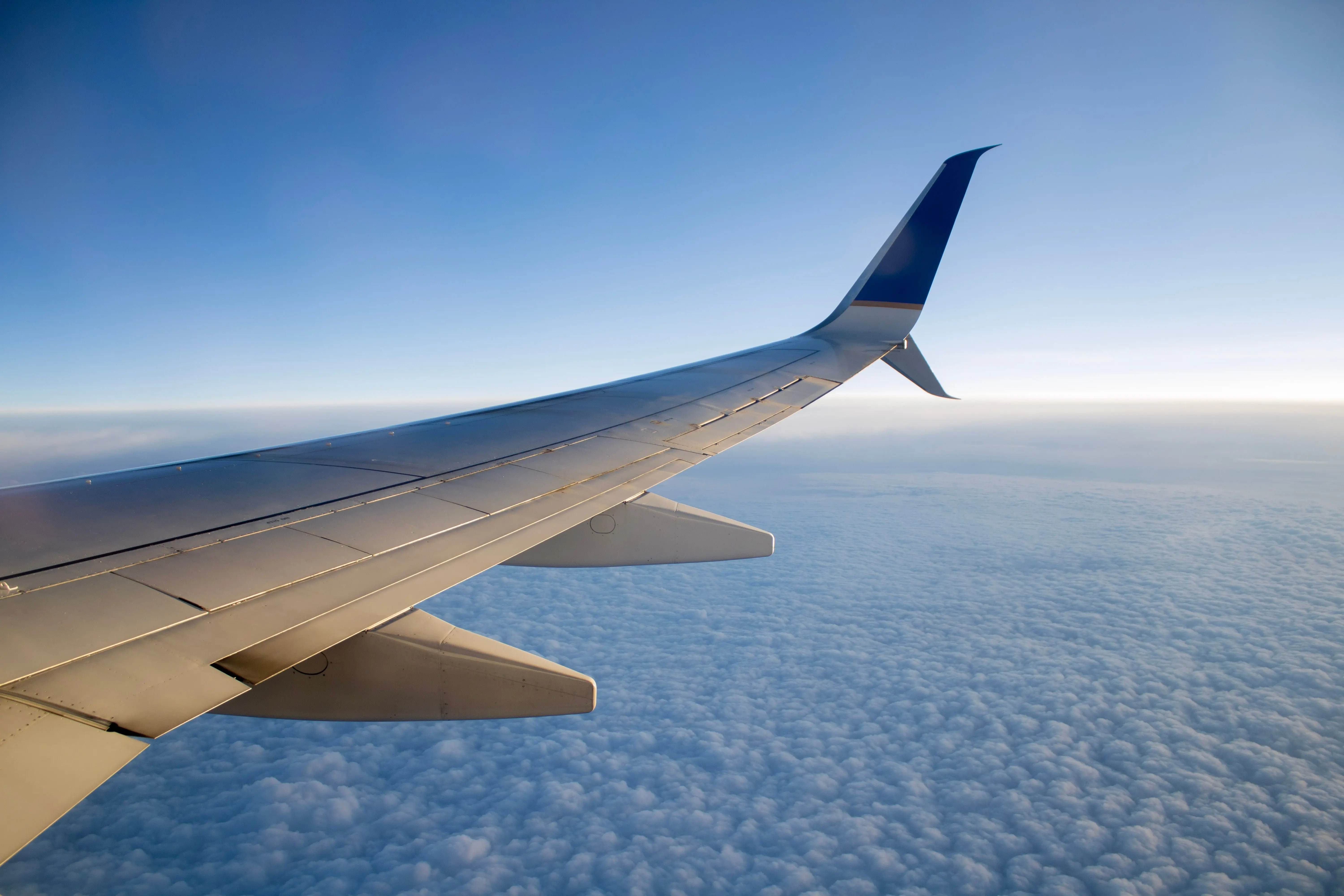 beautiful-shot-of-an-airplane-wing-over-a-layer-of-clouds-in-a-blue-sky