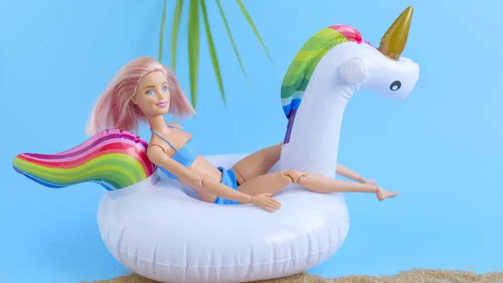 creative-composition-of-a-doll-with-pink-hair-and-swan-unicorn-inflatable-toy-the-concept-of-summer-relaxation-and-travel