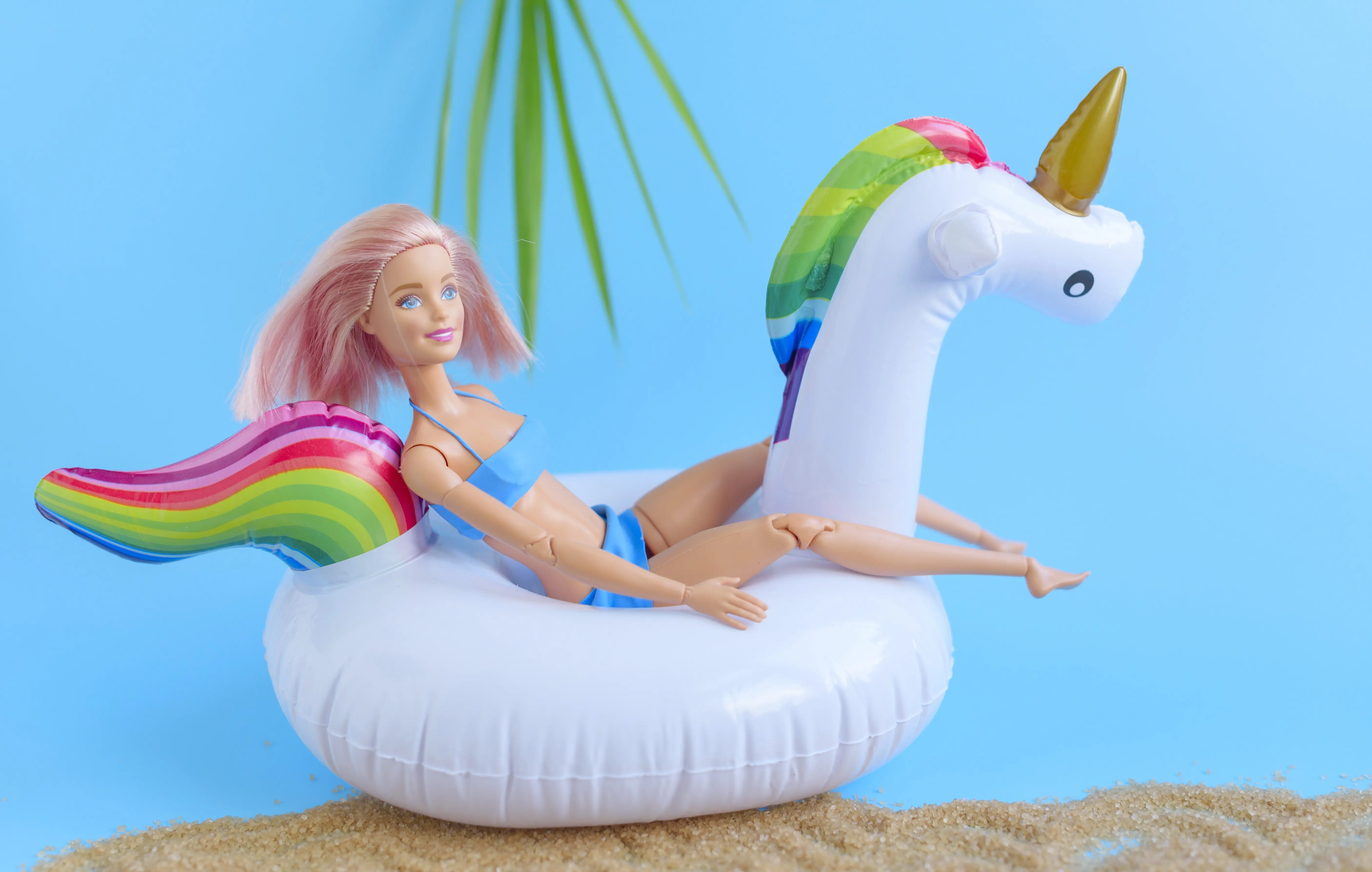 creative-composition-of-a-doll-with-pink-hair-and-swan-unicorn-inflatable-toy-the-concept-of-summer-relaxation-and-travel