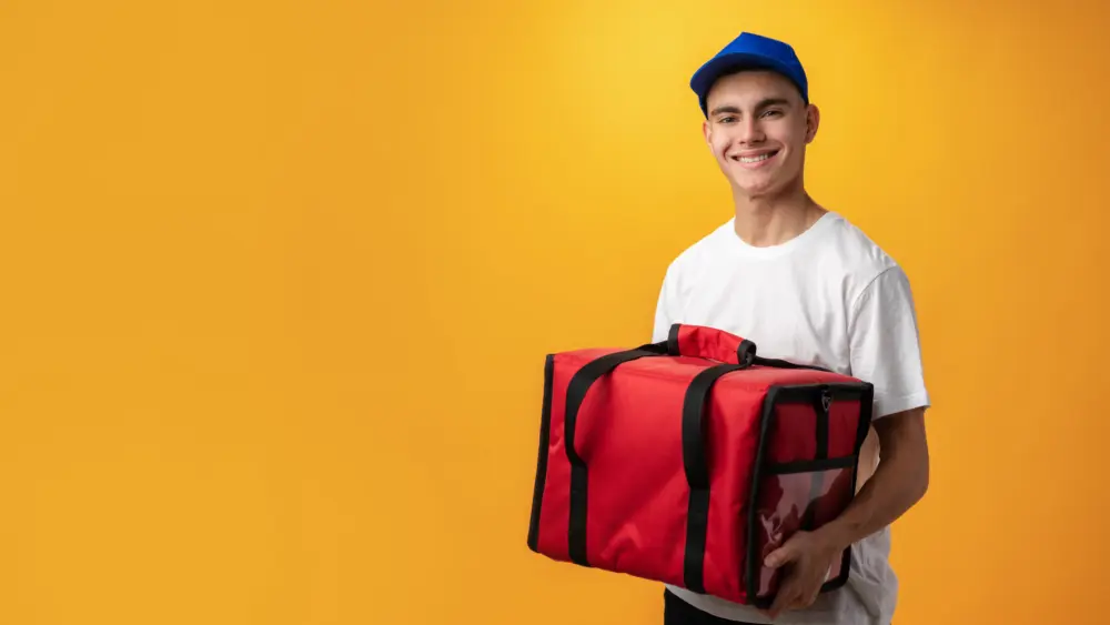 portrait-of-pizza-delivery-boy-with-thermal-bag-against-yellow-background