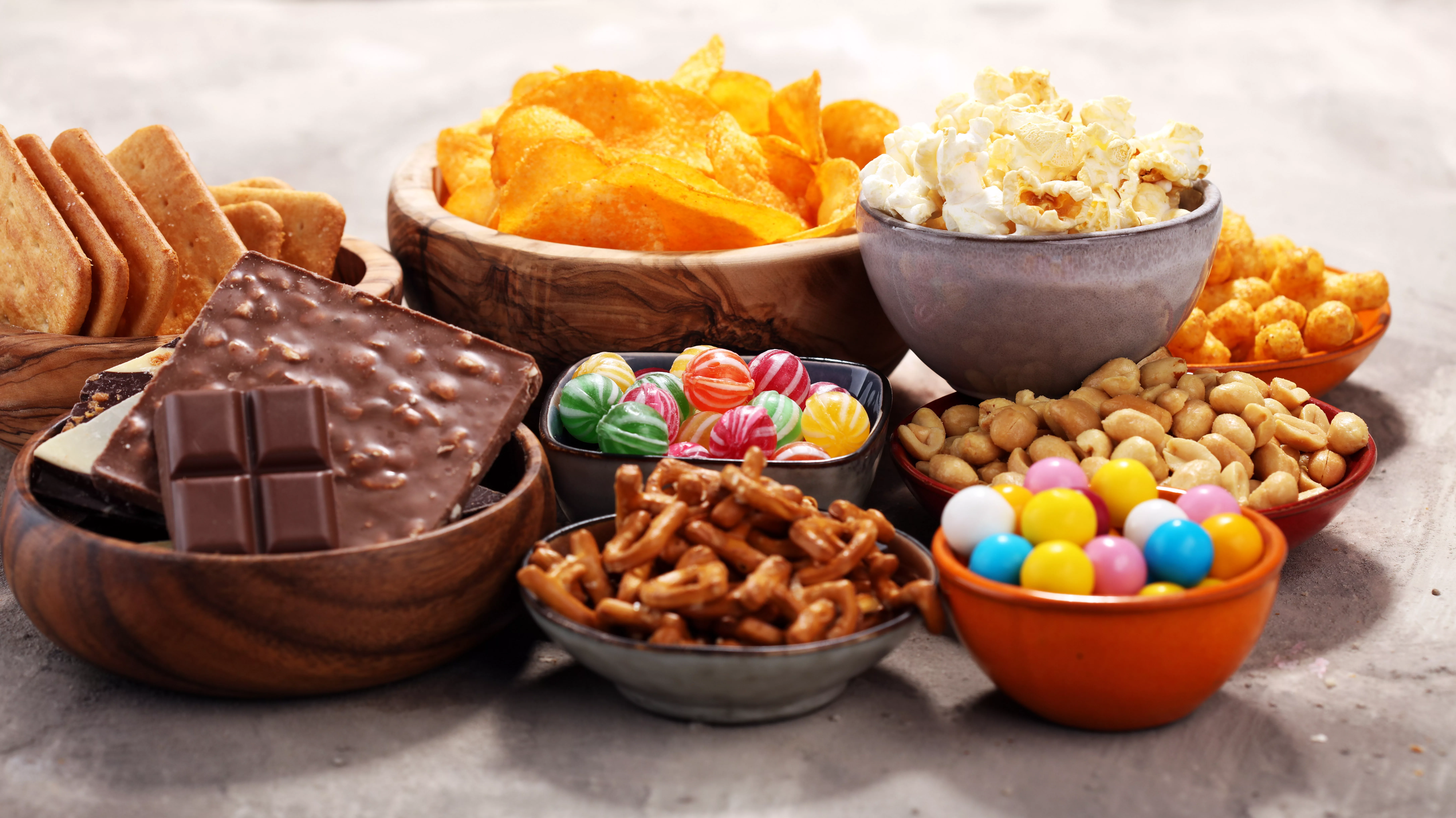 Salty snacks. Pretzels, chips, crackers in wooden bowls. Unhealthy products. food bad for figure, skin, heart and teeth. Assortment of fast carbohydrates food.