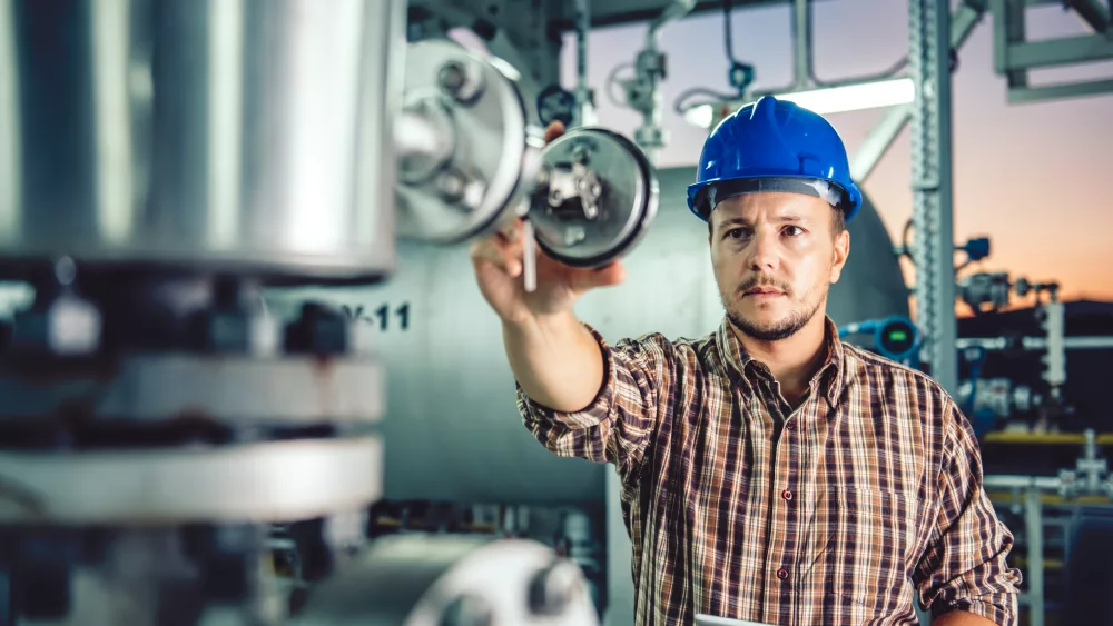 manwearingbluehardhatusingtabletatnaturalgasprocessing