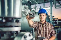 manwearingbluehardhatusingtabletatnaturalgasprocessing